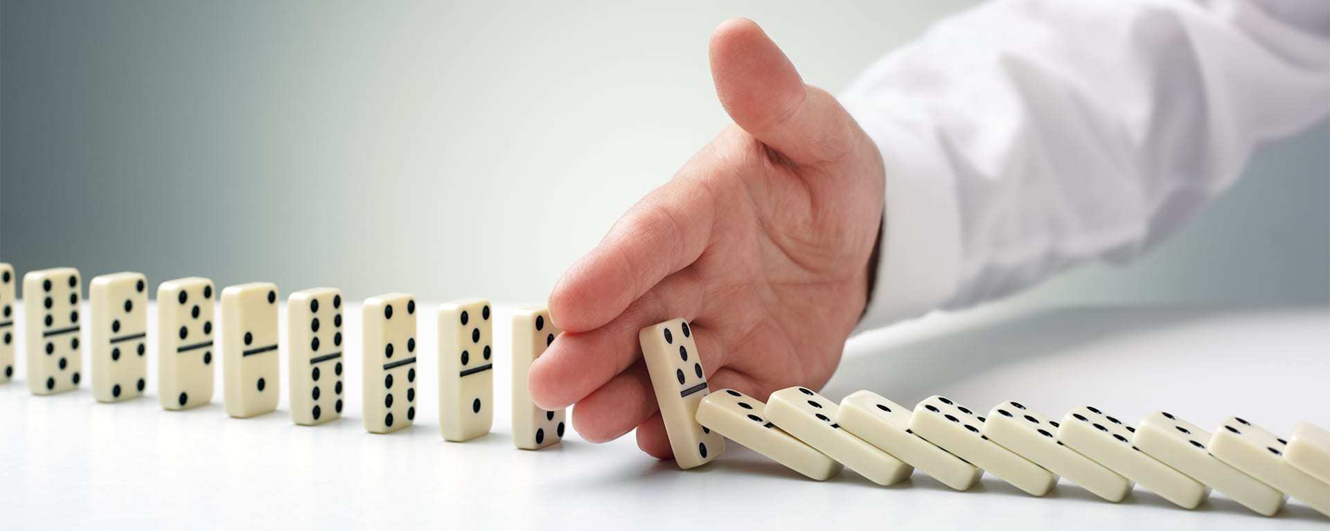 Image of falling dominos being stopped by Swartz Consulting services