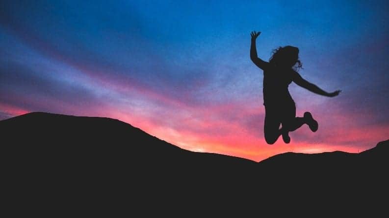 happy person jumping at dawn